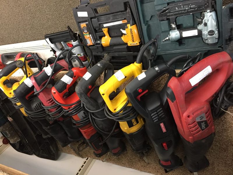 A row of used reciprocating saws and nail guns for sale